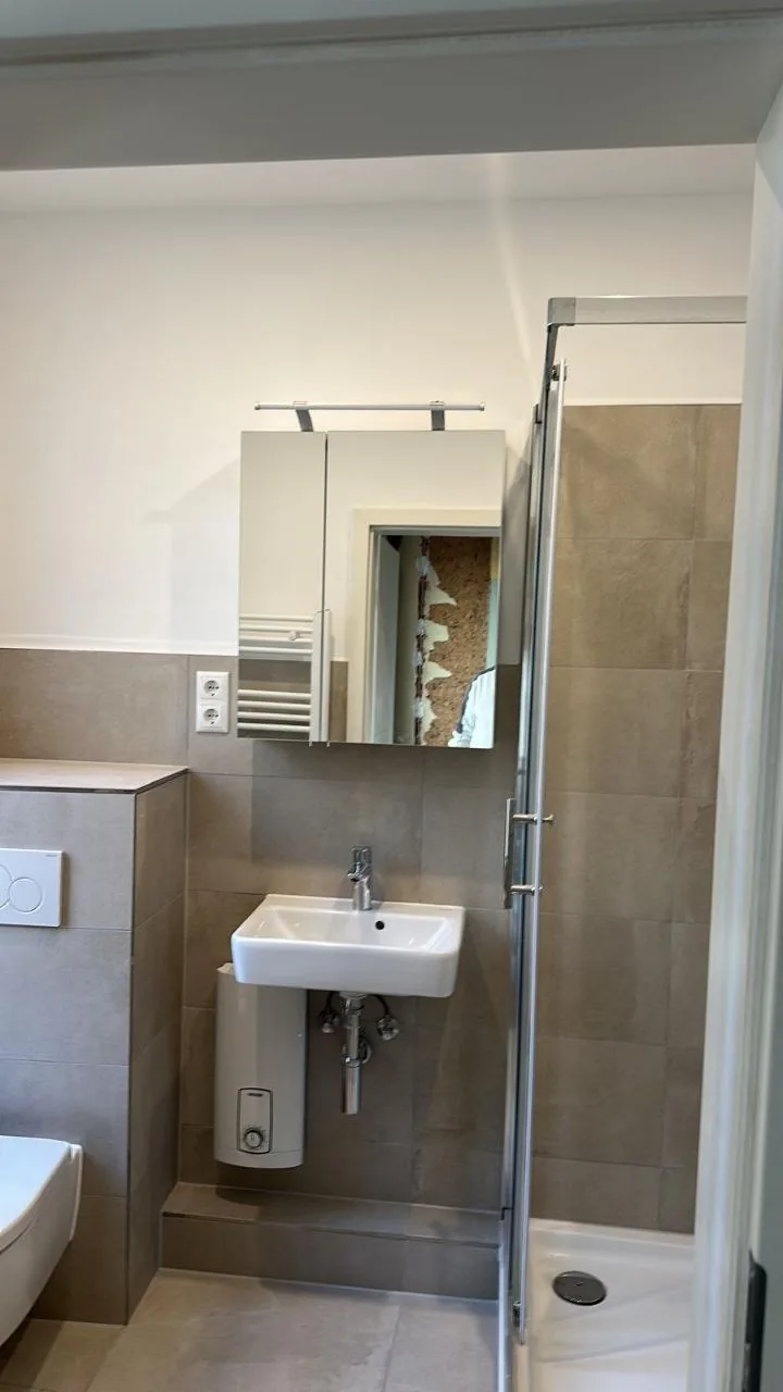 Nachher: Dusche mit Spiegelschrank und grauen Fliesen