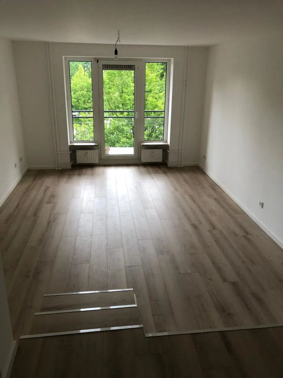 Wohnzimmer mit Balkonfenster und hellem Gesamtbild nach Renovierung